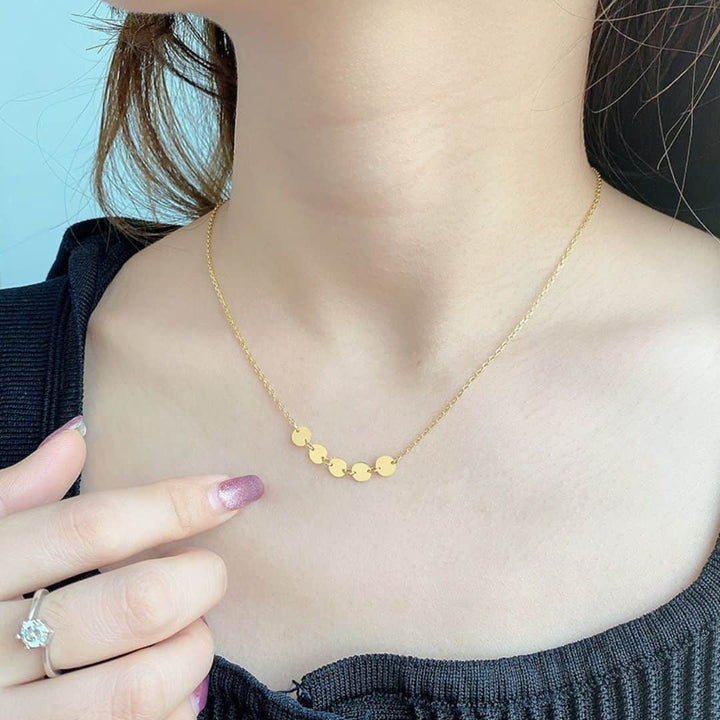 Close-up of a delicate mini disc necklace in gold, highlighting its dainty and chic design, ideal for casual and formal outfits.